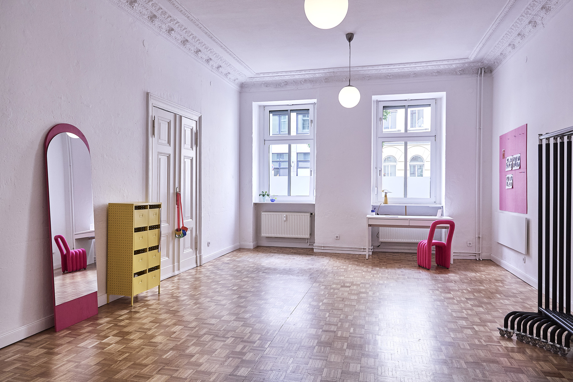 Wide view of the Fitting Room — daylight, parquet floor, arched mirror and steel rail