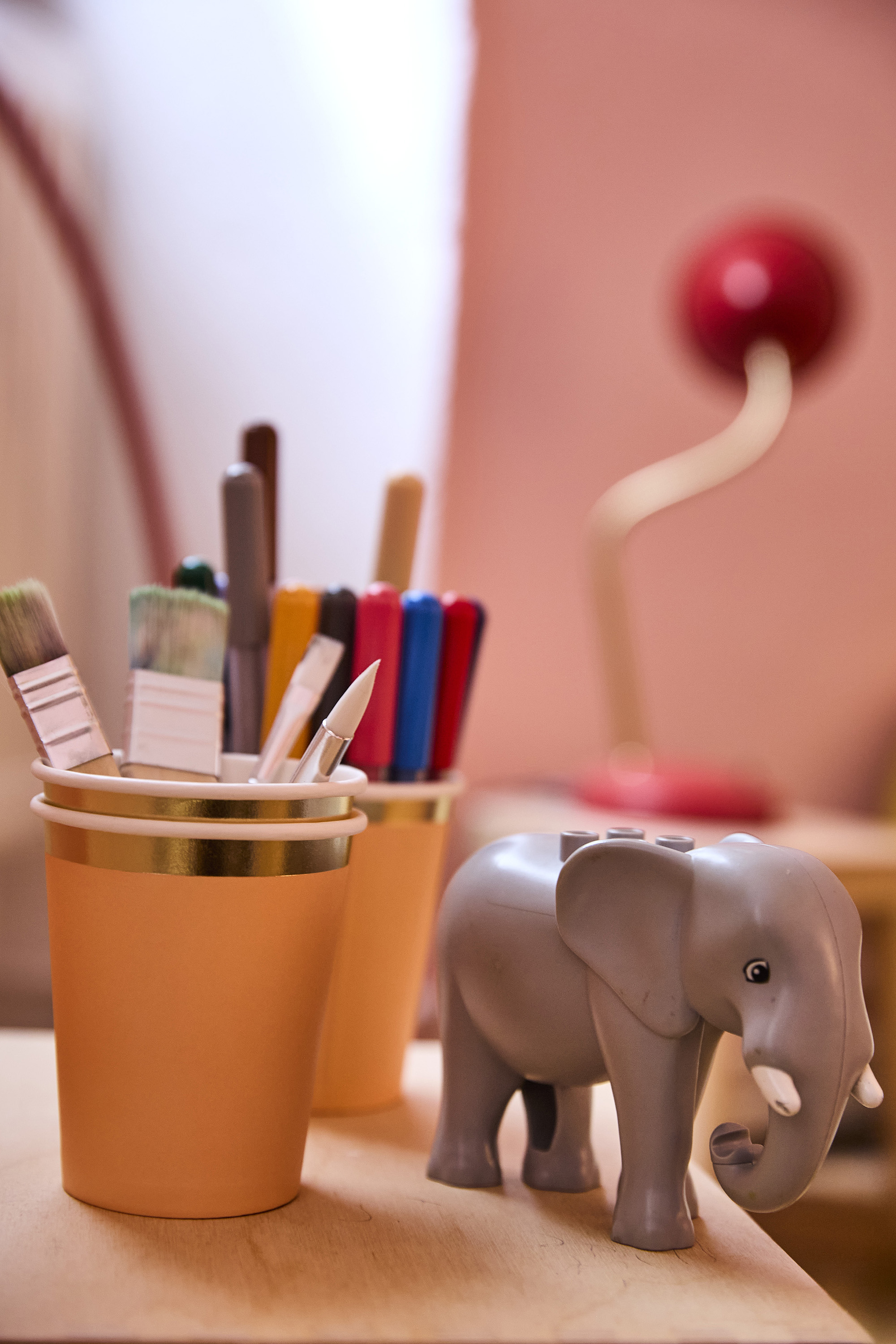 Kids' corner detail — cups of pens and a toy elephant on a desk