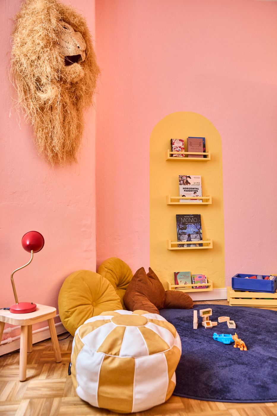 The Kids' Corner — pink walls, book shelf, cushions and toys on a rug