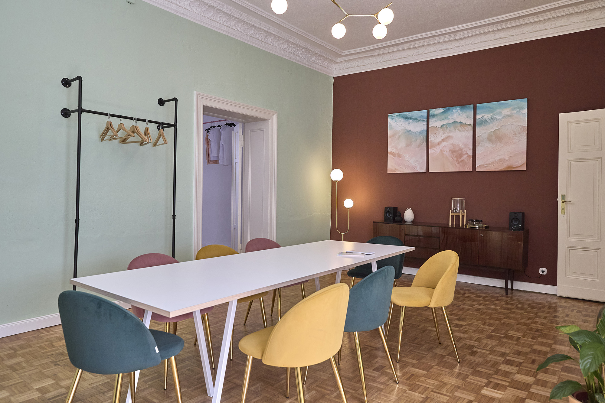The Meeting Room — sage-green and terracotta walls, velvet chairs around the white table, ocean triptych on the wall